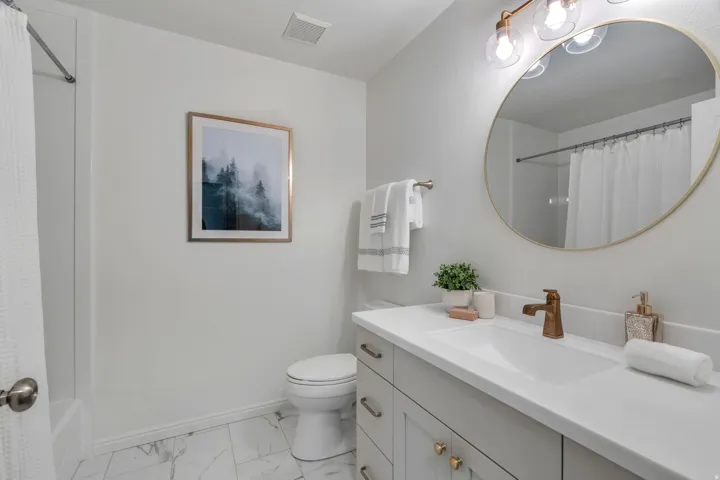 Bathroom with vanity, light marble finish floors, and shower / tub combo with curtain