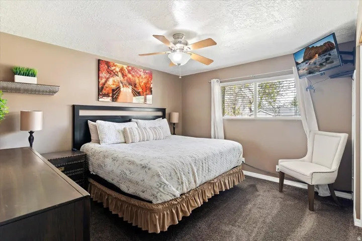 Bedroom featuring dark colored carpet, a textured ceiling, and a ceiling fan