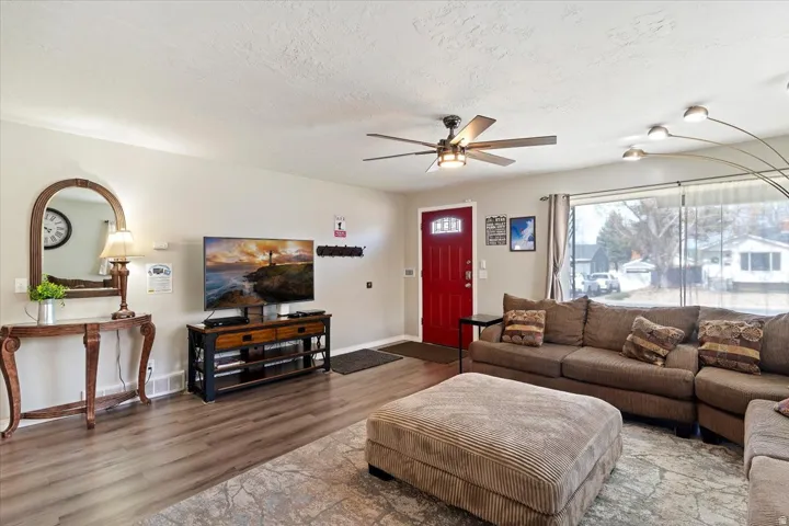 Living area with LVP floors, a ceiling fan, and large picture window