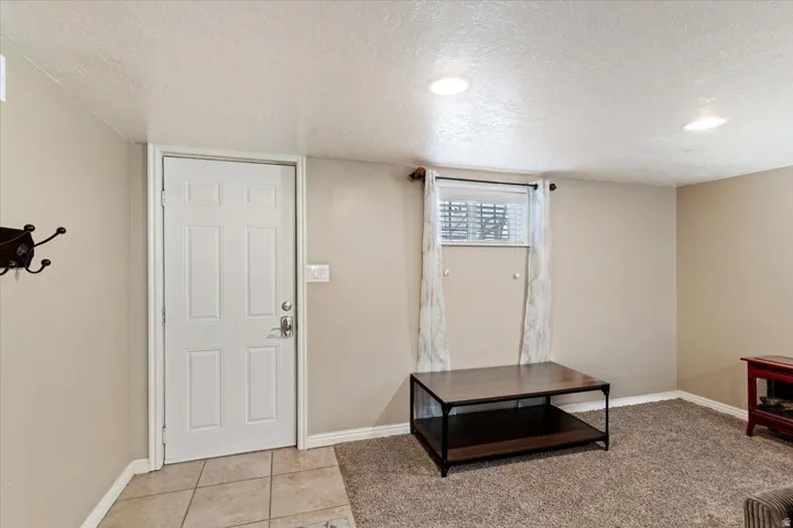 Basement exterior entry door, foyer with a textured ceiling and light tile flooring