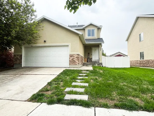 View of front of house with brick siding, stucco siding, an attached garage, concrete driveway, and a porch