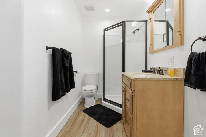 Full bathroom with a stall shower, vanity, and light wood-style flooring