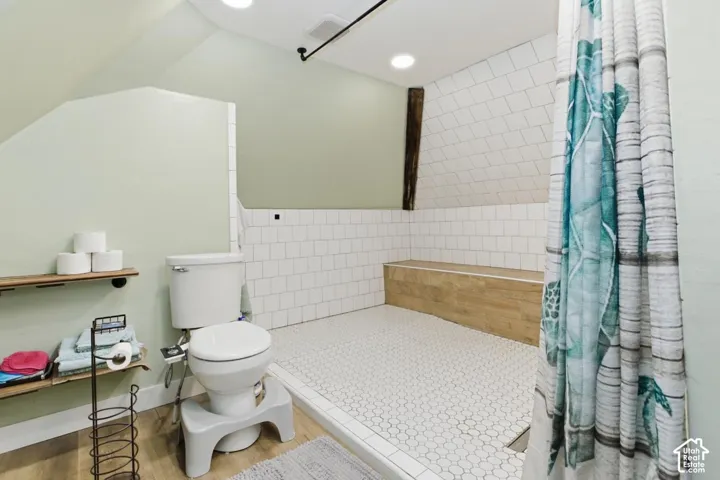 Full bathroom with wood finished floors, tiled shower, and recessed lighting