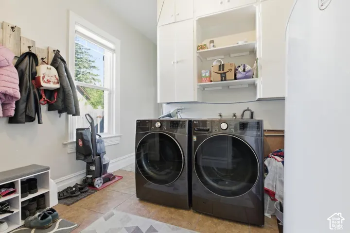 Laundry room featuring independent washer and dryer, light tile patterned floors, and cabinet space