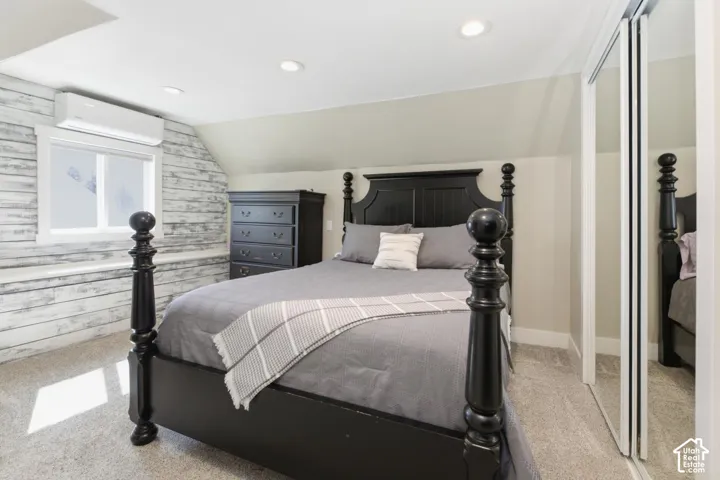 Bedroom with light carpet, vaulted ceiling, a closet, recessed lighting, and wooden walls