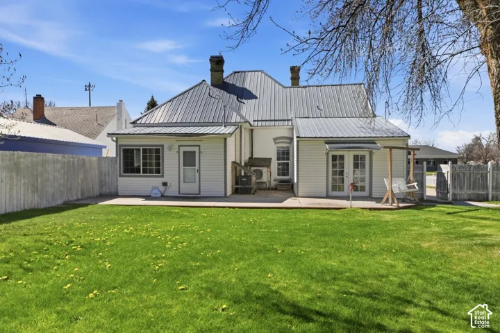 Rear view of house featuring a fenced backyard, a patio area, and a metal roof