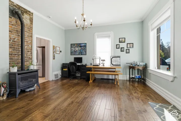 Office area featuring a wood stove, dark wood-style floors, crown molding, and suspended lighting