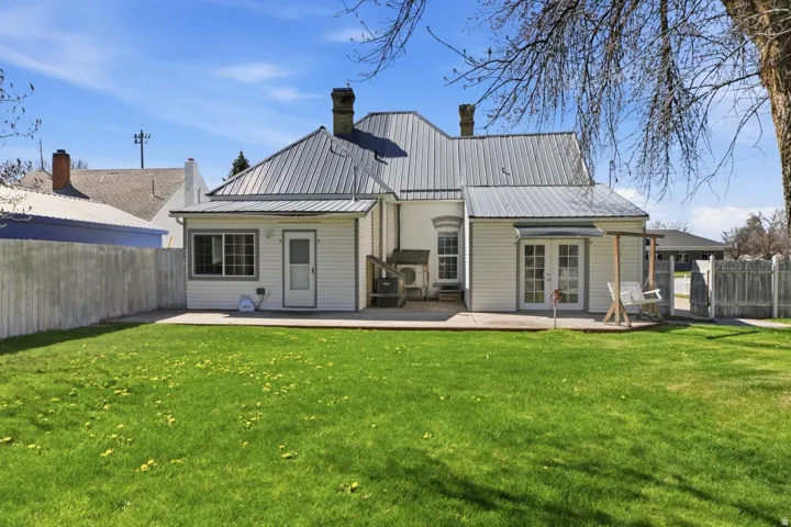Rear view of house featuring a fenced backyard, a patio area, and a metal roof