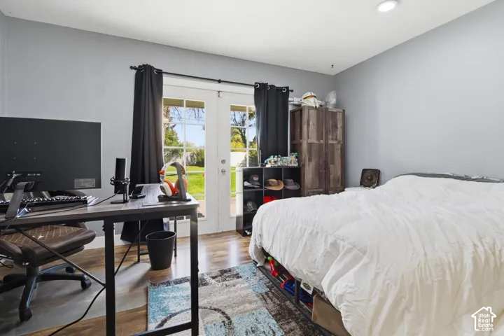 Bedroom with wood finished floors, a desk, access to exterior, and french doors