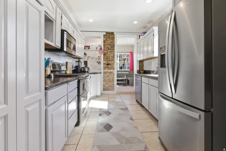 Kitchen featuring stainless steel appliances, light tile patterned floors, white cabinets, dark countertops, and recessed lighting