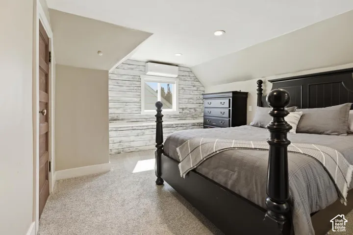 Bedroom with lofted ceiling, light colored carpet, wooden walls, and recessed lighting