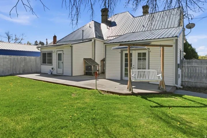 Back of property with a chimney, a patio, and a metal roof