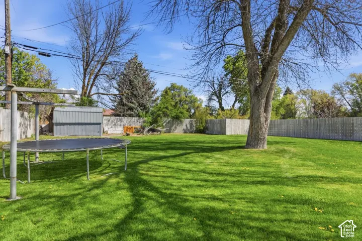 Fenced backyard featuring a storage shed and a trampoline