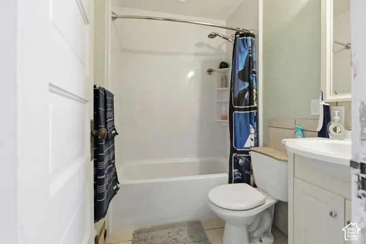Bathroom featuring vanity, shower / bathtub combination with curtain, and light tile patterned floors