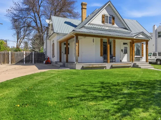 Modern farmhouse style home featuring a large porch, a chimney, brick siding, and a standing seam roof