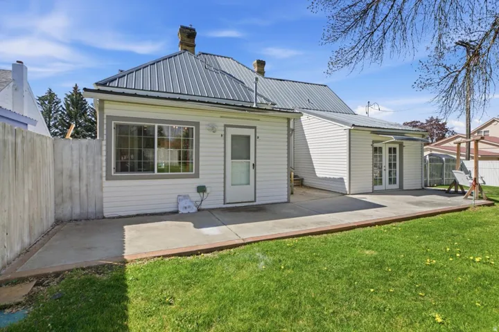 Back of house with a fenced backyard, a metal roof, a chimney, and a wooden deck