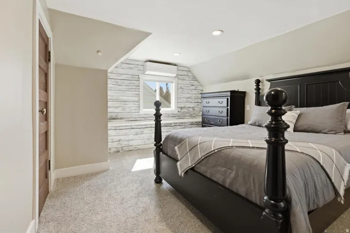 Bedroom with lofted ceiling, light colored carpet, wooden walls, and recessed lighting