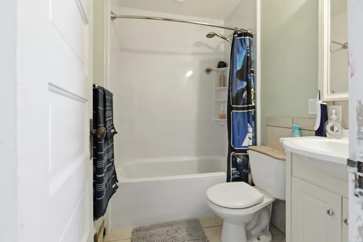 Bathroom featuring vanity, shower / bathtub combination with curtain, and light tile patterned floors