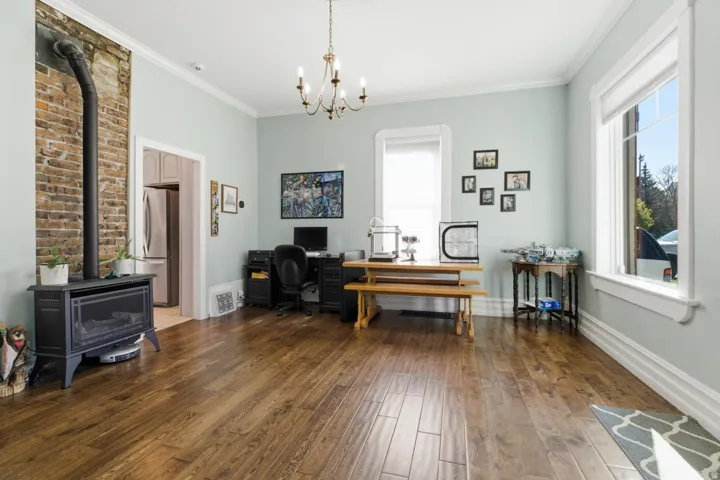 Office area featuring a wood stove, dark wood-style floors, crown molding, and suspended lighting