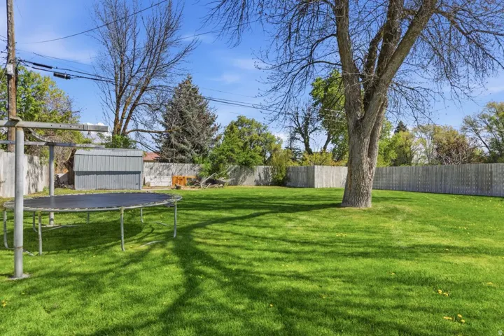 Fenced backyard featuring a storage shed and a trampoline