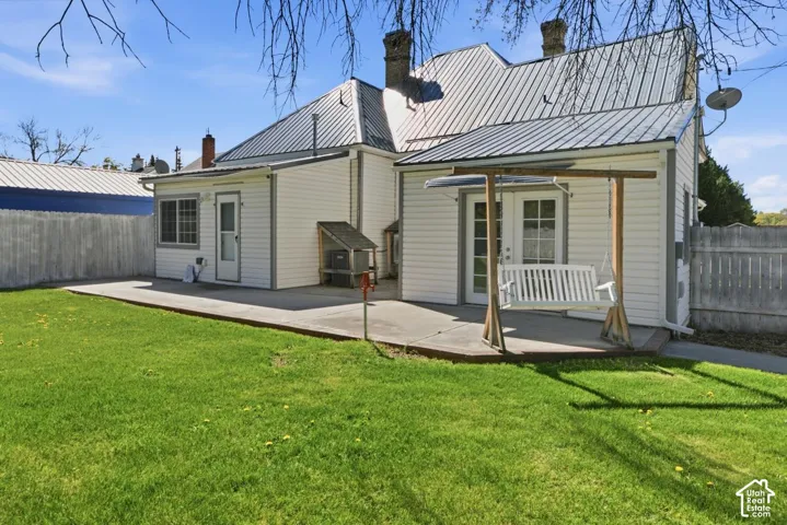 Back of property with a chimney, a patio, and a metal roof