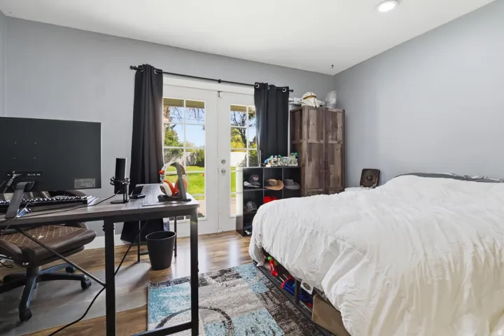 Bedroom with wood finished floors, a desk, access to exterior, and french doors