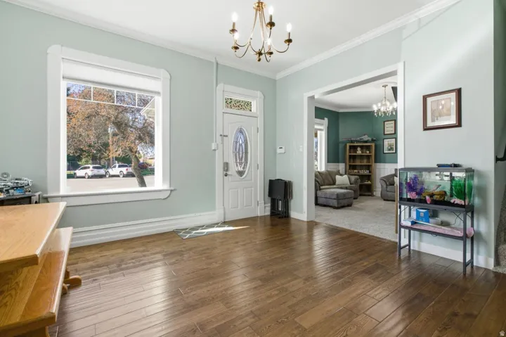 Entrance foyer with suspended lighting, crown molding, and dark wood-style flooring