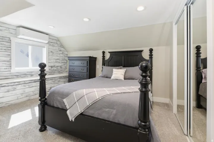 Bedroom with light carpet, vaulted ceiling, a closet, recessed lighting, and wooden walls