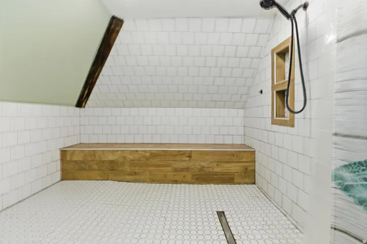 Full bathroom with tile walls, a tile shower, and lofted ceiling