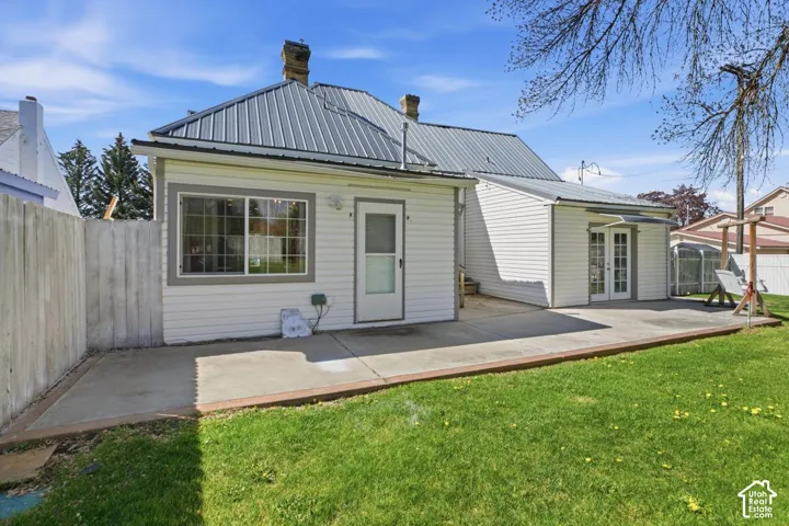 Back of house with a fenced backyard, a metal roof, a chimney, and a wooden deck