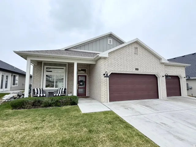 View of front of property with a garage, covered porch, board and batten siding, driveway, and a front yard