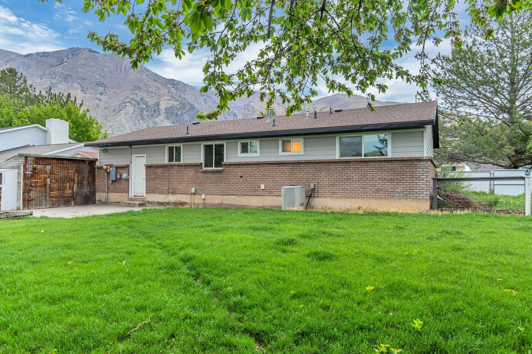 Back of property with brick siding, a patio, a mountain view, and an outdoor structure