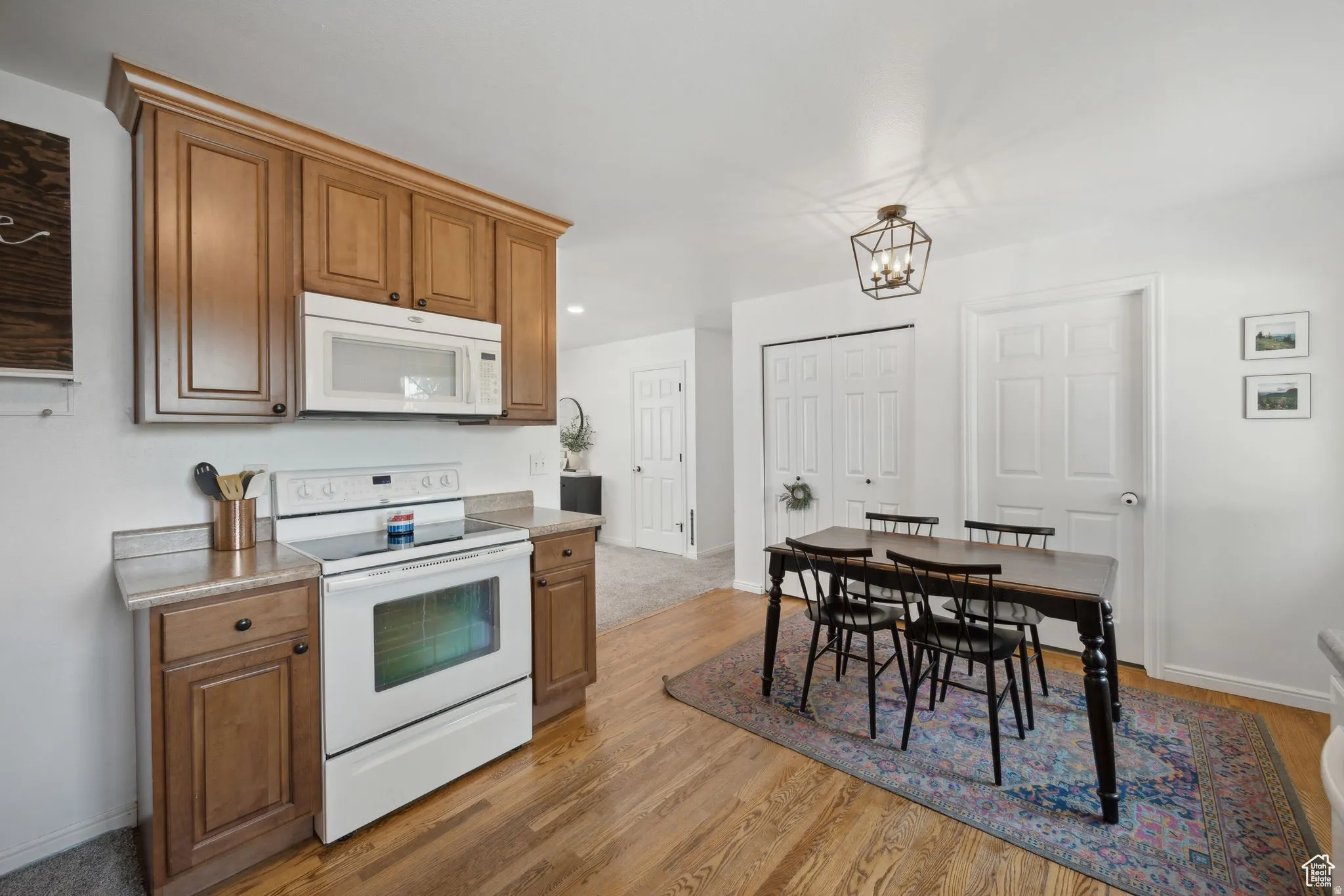 Kitchen featuring white appliances, wood finish cabinets, light wood finished floors, and light countertops