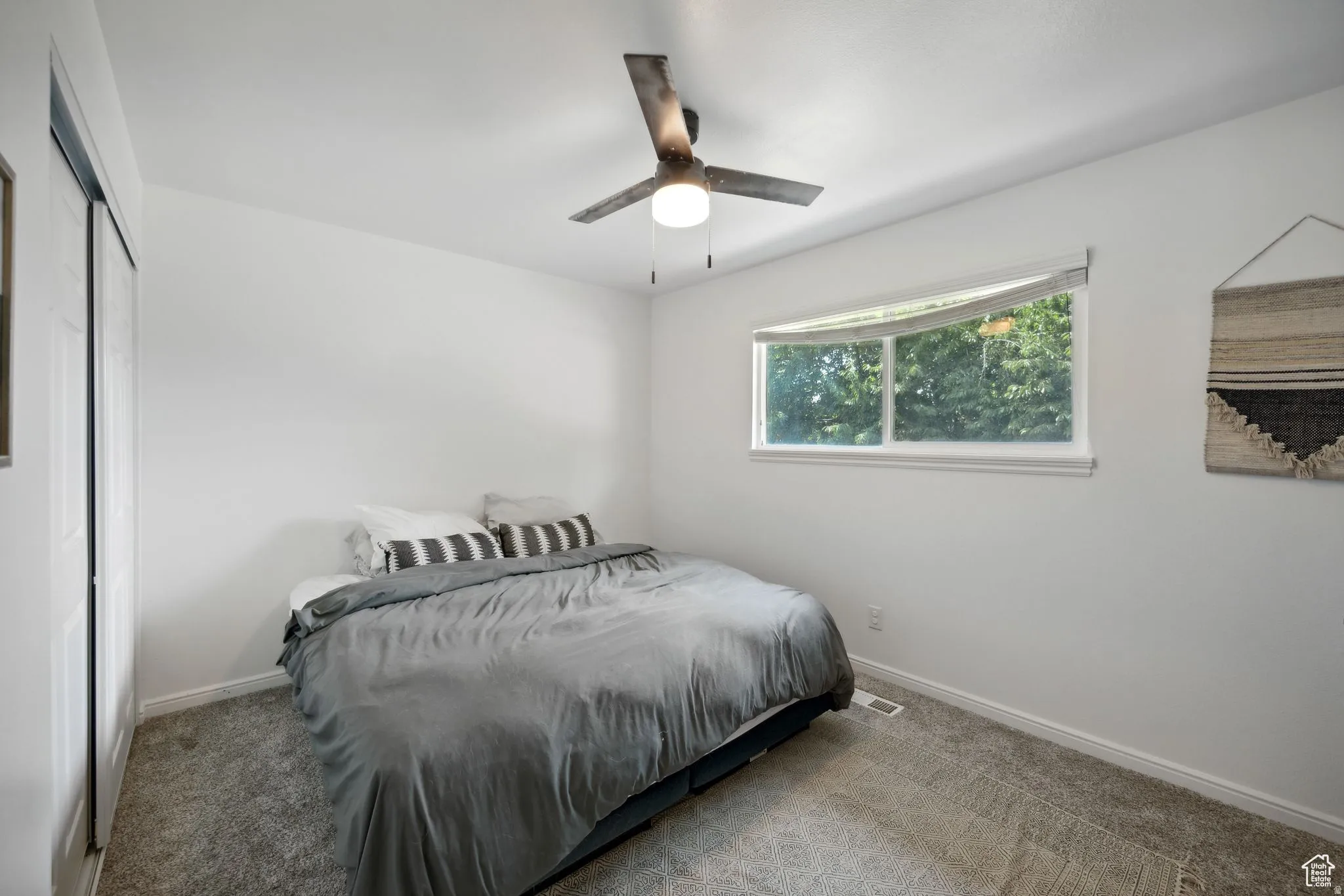 Carpeted bedroom with a closet and ceiling fan