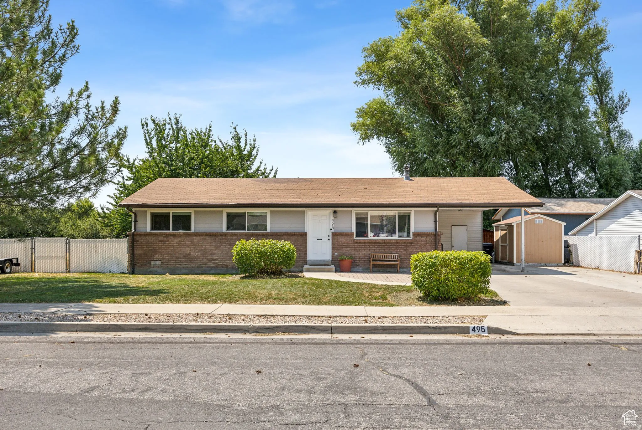 View of front of home featuring a storage unit and brick siding