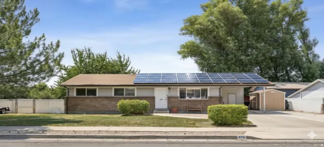 Ranch-style residence featuring solar panels, a partial brick facade, and a covered carport