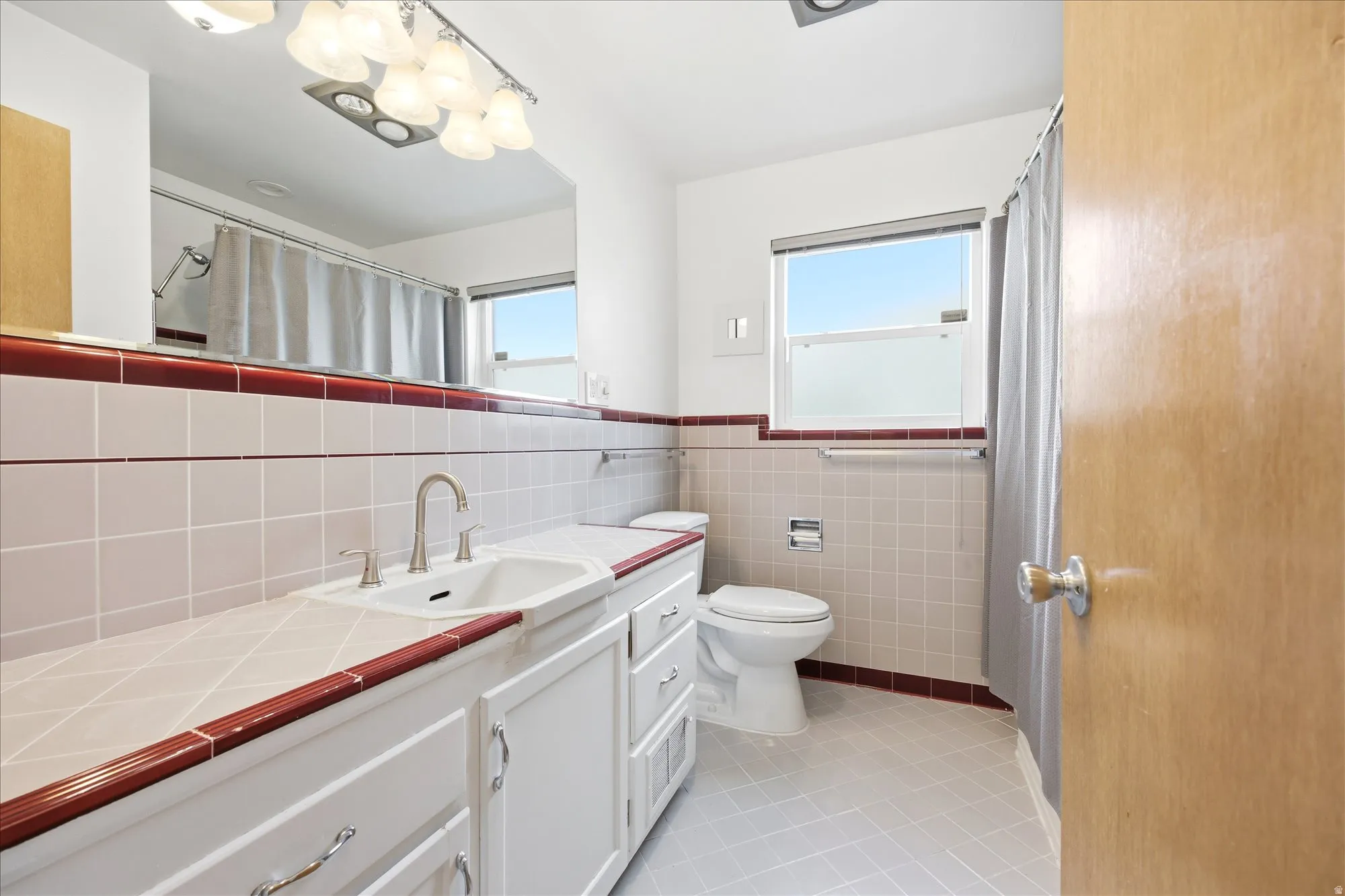 Bathroom featuring vanity, light tile patterned floors, tile walls, wainscoting, and a shower with shower curtain
