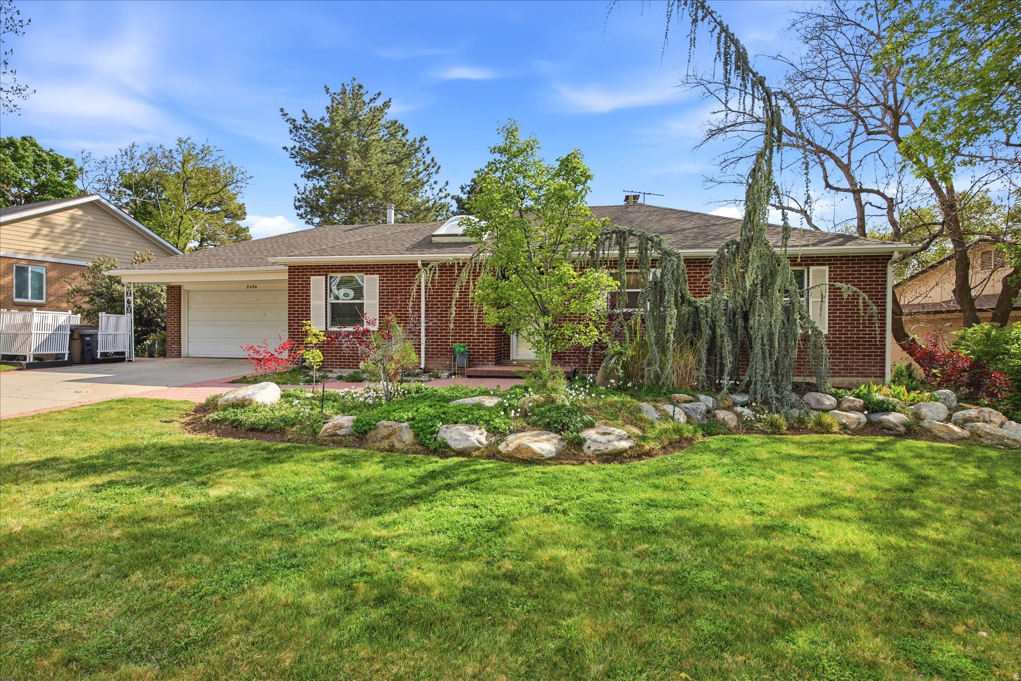 Ranch-style home featuring brick siding, a garage, a front lawn, driveway, and roof with shingles
