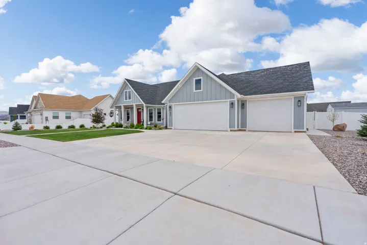 View of front facade featuring board and batten siding, a shingled roof, driveway, and an attached garage