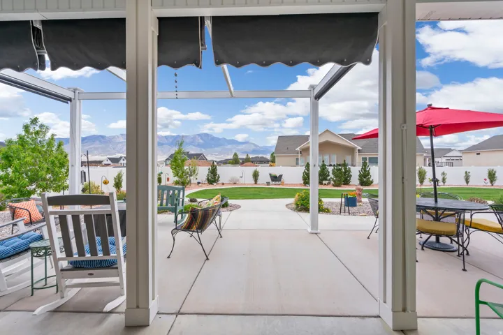 Fenced backyard featuring outdoor dining area, a patio area, a mountain view, a sunroom, and a residential view