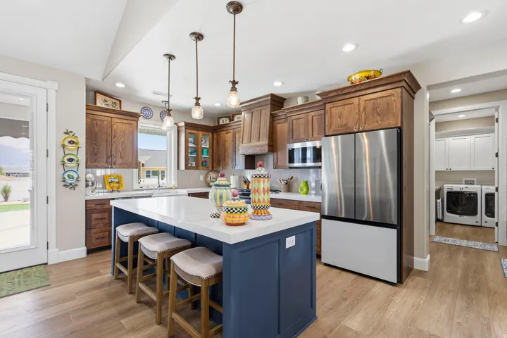 Dual tone kitchen featuring stainless steel appliances, a breakfast bar, a kitchen island, hanging light fixtures, and light wood-style floors
