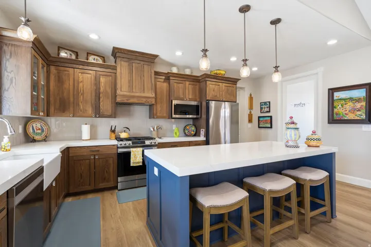 Kitchen featuring stainless steel appliances, backsplash, light wood-style flooring, a kitchen bar, and pendant lighting