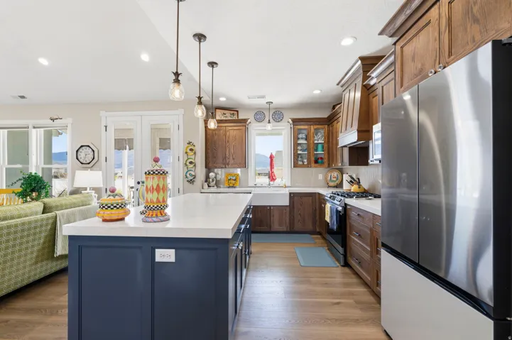 Kitchen with stainless steel appliances, a center island, glass fronted cabinets, open floor plan, and light wood-style floors