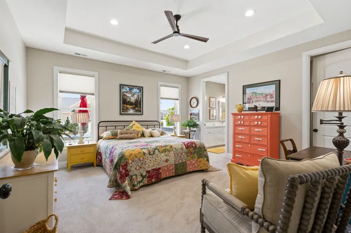 Bedroom featuring a raised ceiling, light carpet, ceiling fan, ensuite bathroom, and recessed lighting