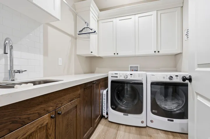 Laundry room with washing machine and dryer, light wood-type flooring, and cabinet space