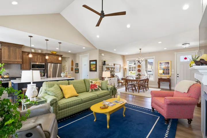 Living area featuring ceiling fan, dark wood-style flooring, lofted ceiling, a fireplace, and suspended lighting