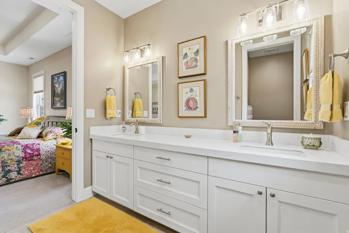 Ensuite bathroom with double vanity and light colored carpet