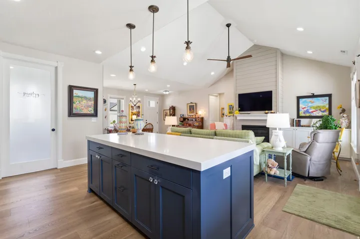 Kitchen with open floor plan, blue cabinets, a kitchen island, ceiling fan, and light wood finished floors