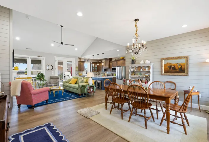 Dining area featuring wooden walls, light wood-style floors, ceiling fan, a chandelier, and vaulted ceiling