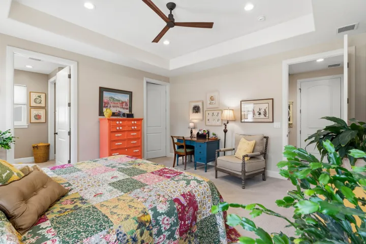Bedroom featuring a tray ceiling, light carpet, ceiling fan, recessed lighting, and connected bathroom